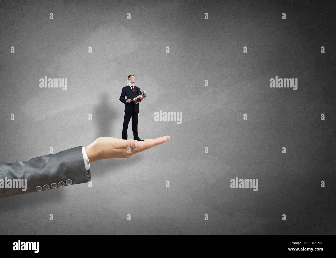 Grande paume femelle tenant petit homme d'affaires confiant jouer tambour Banque D'Images