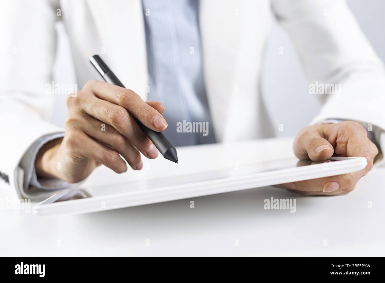 Homme en costume d'affaires blanc à l'aide d'un ordinateur tablette. Gros plan de mains masculines tenant un stylo et un gadget de tablette. Appareil intelligent mobile dans l'activité professionnelle. Activé Banque D'Images