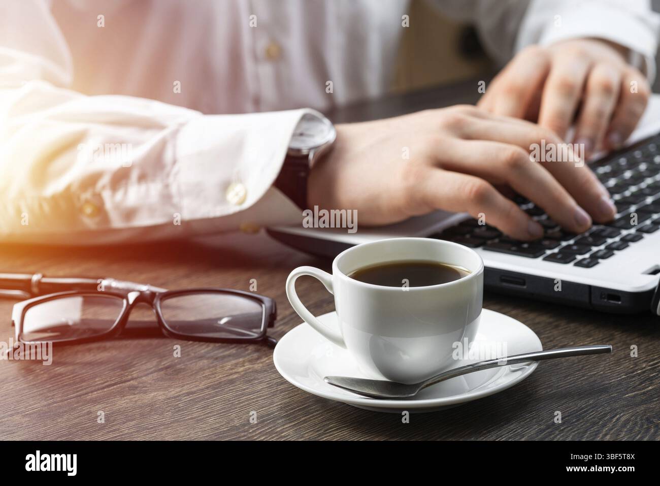 Homme d'affaires assis au bureau et utilisant un ordinateur portable. Gros plan sur les mains de l'homme tapant sur le clavier au bureau. Espace de consultation avec vue latérale avec lunettes et Banque D'Images