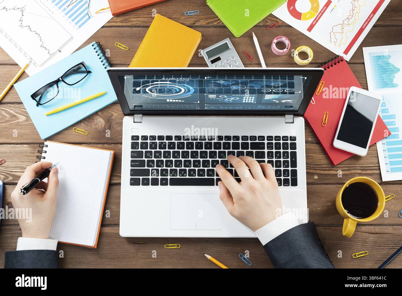 Gros plan des mains d'homme d'affaires travaillant à l'ordinateur portable. Bureau vue de dessus avec ordinateur et documents financiers sur table en bois. Profession commerciale des Banque D'Images
