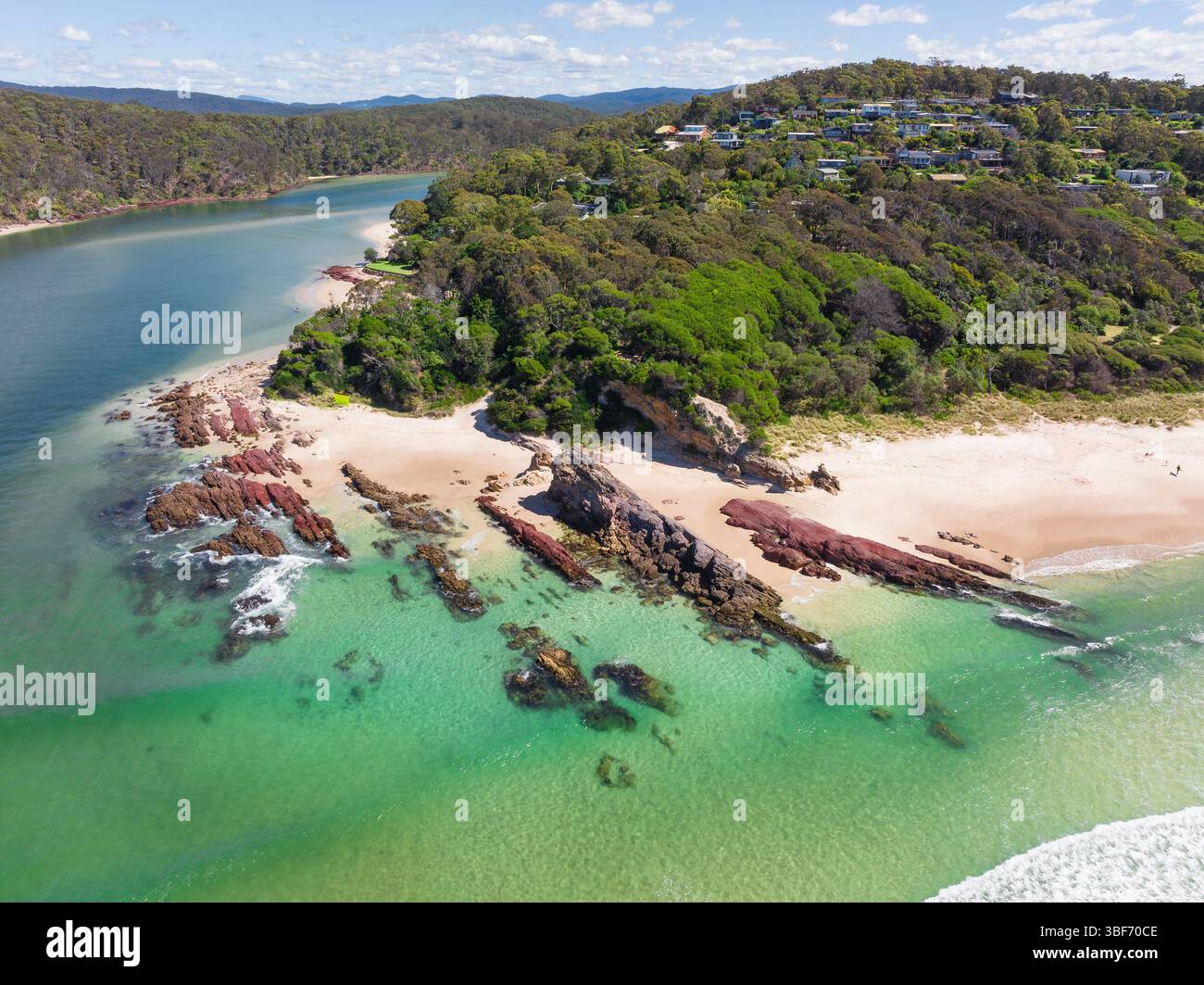 Vue aérienne de couches de roche rouge à l'embouchure d'une rivière côtière à Pambula Beach sur la Sapphire Coast de Nouvelle-Galles du Sud en Australie. Banque D'Images