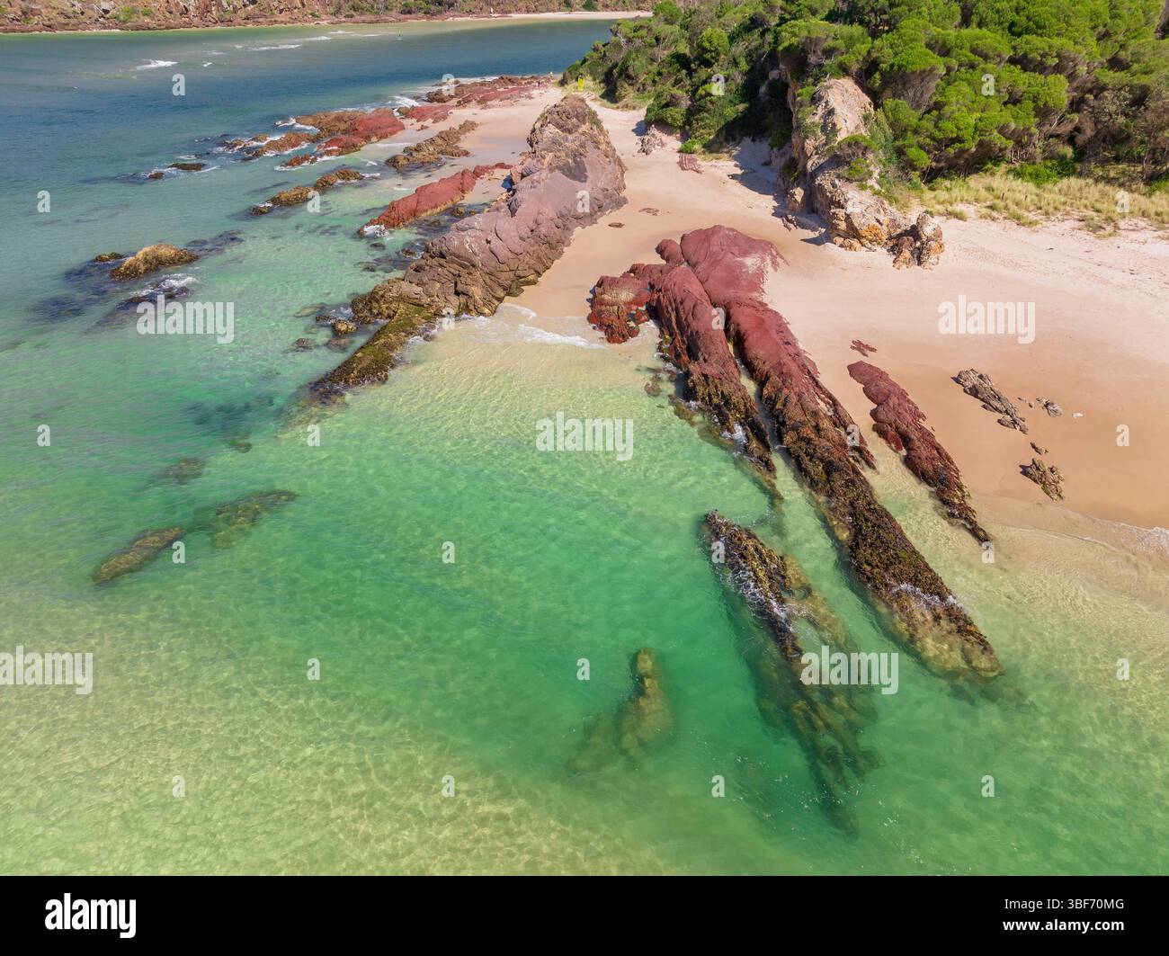 Vue aérienne de couches de roche rouge à l'embouchure d'une rivière côtière à Pambula Beach sur la Sapphire Coast de Nouvelle-Galles du Sud en Australie. Banque D'Images