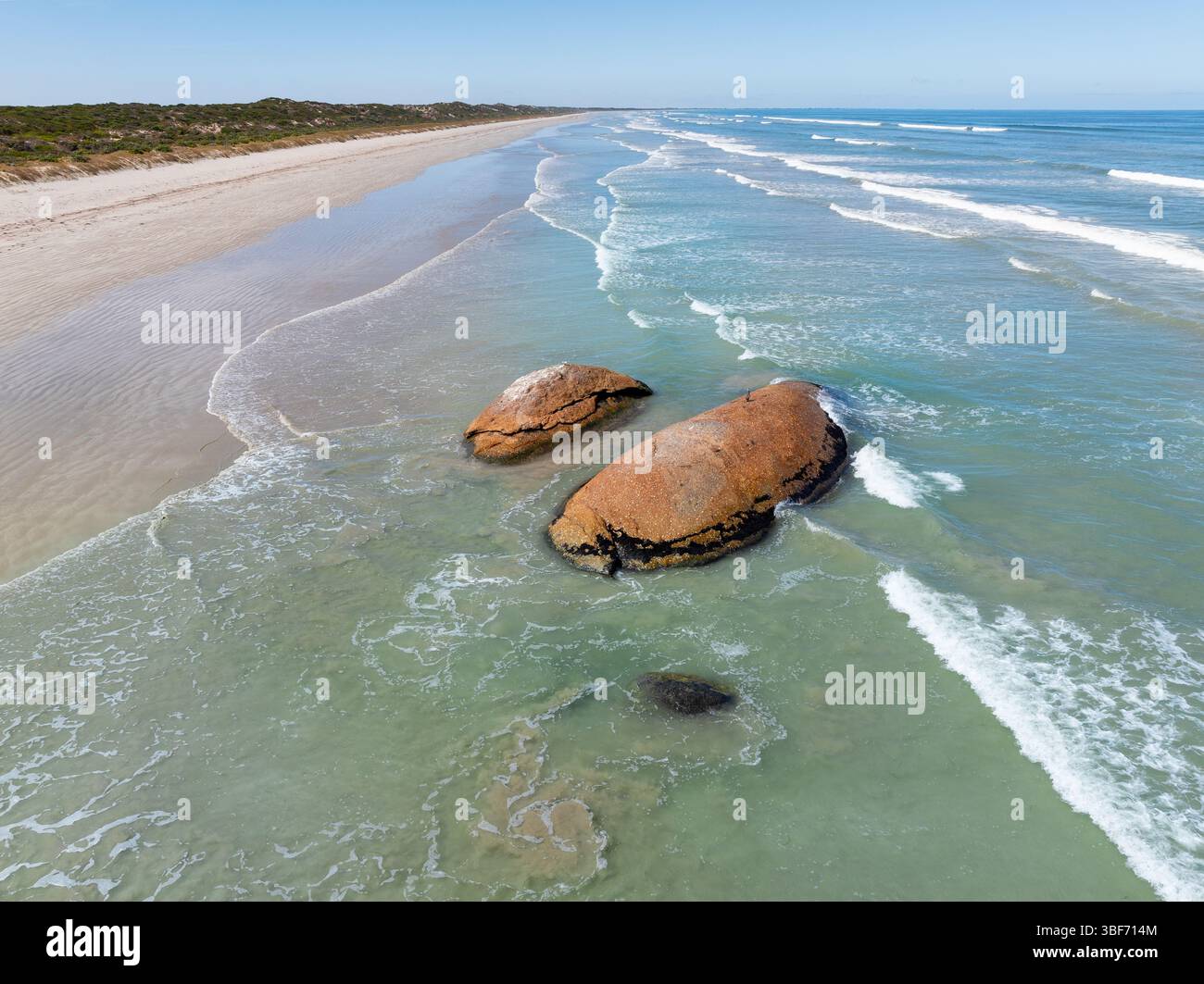 Vue aérienne des vagues qui roulent autour de grands harpons de granit sur une longue plage de sable à Granites sur la côte calcaire de l'Australie méridionale. Banque D'Images