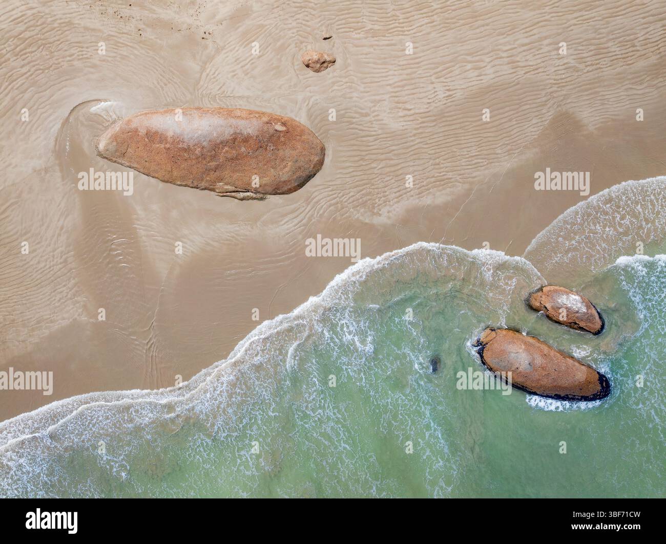 Vue aérienne des vagues qui roulent autour de grands harpons de granit sur une longue plage de sable à Granites sur la côte calcaire de l'Australie méridionale. Banque D'Images