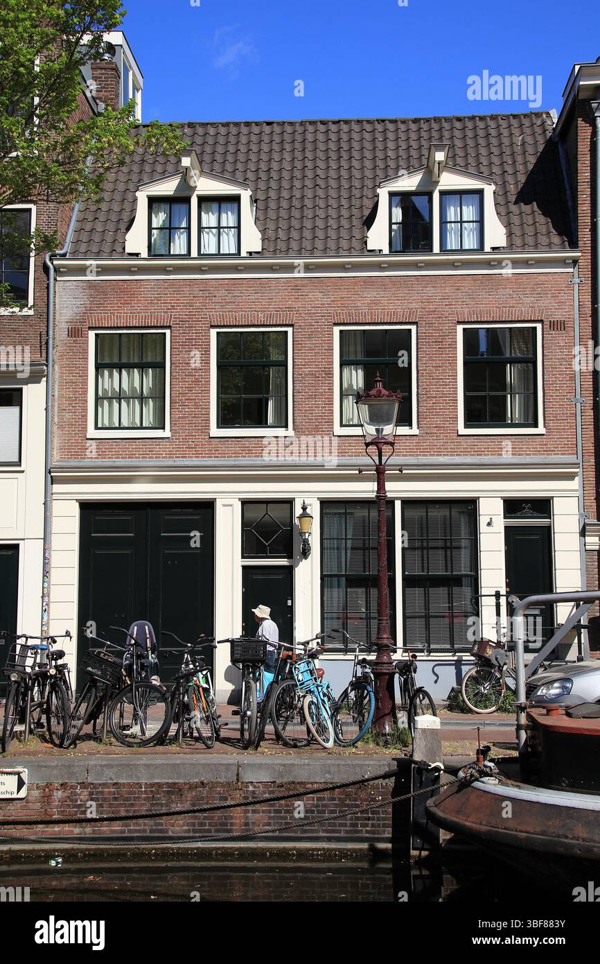 Vue sur la rue Bloemgracht avec façade de maison hollandaise typique, ancien lampadaire et homme qui marche à Amsterdam, quartier Jordaan, pays-Bas, mai 2025. Banque D'Images