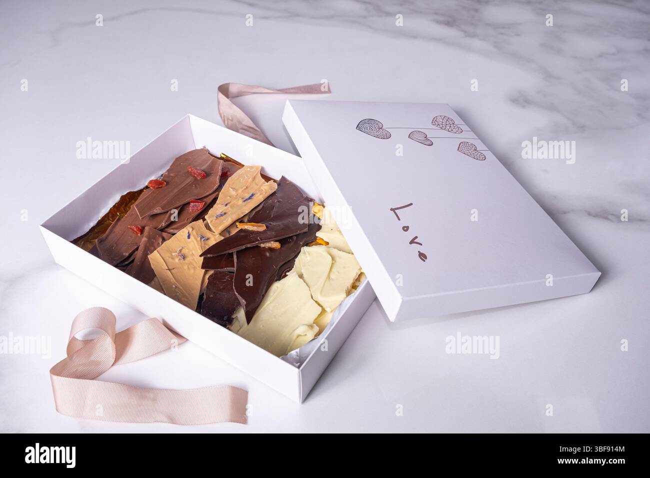 Une boîte blanche ouverte avec des pépites de chocolat assorties. Banque D'Images