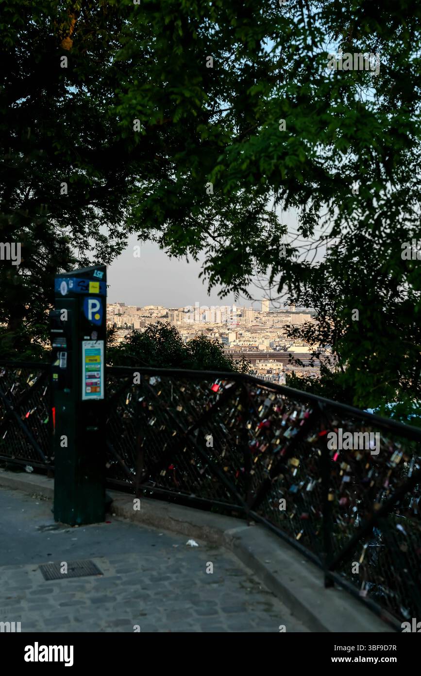 Un point de vue surplombant le paysage urbain de Paris, avec un parcmètre et une clôture densément couverte de serrures d'amour au premier plan immédiat sous l'alose Banque D'Images