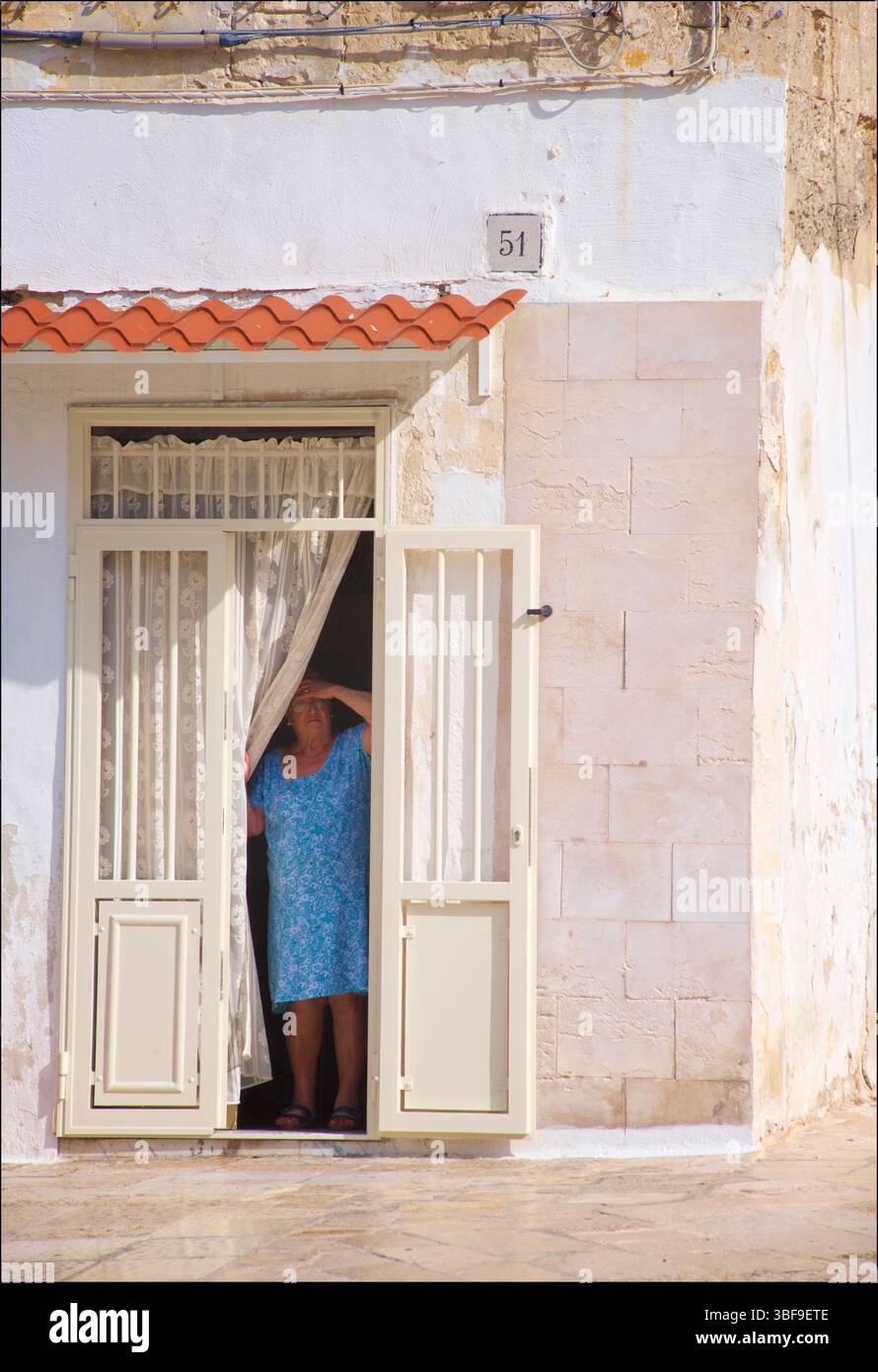Femme italienne regardant par la porte de sa maison, Piazza Federico II di Svevia, Bari, Pouilles, Italie. Banque D'Images