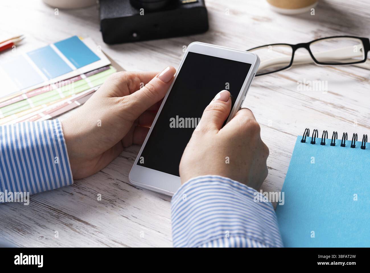 Blogueur assis à son bureau et tenant son smartphone. Les appareils intelligents mobiles dans les processus d'entreprise. Occupation des entreprises et innovation. Travail de bureau d'entreprise Banque D'Images