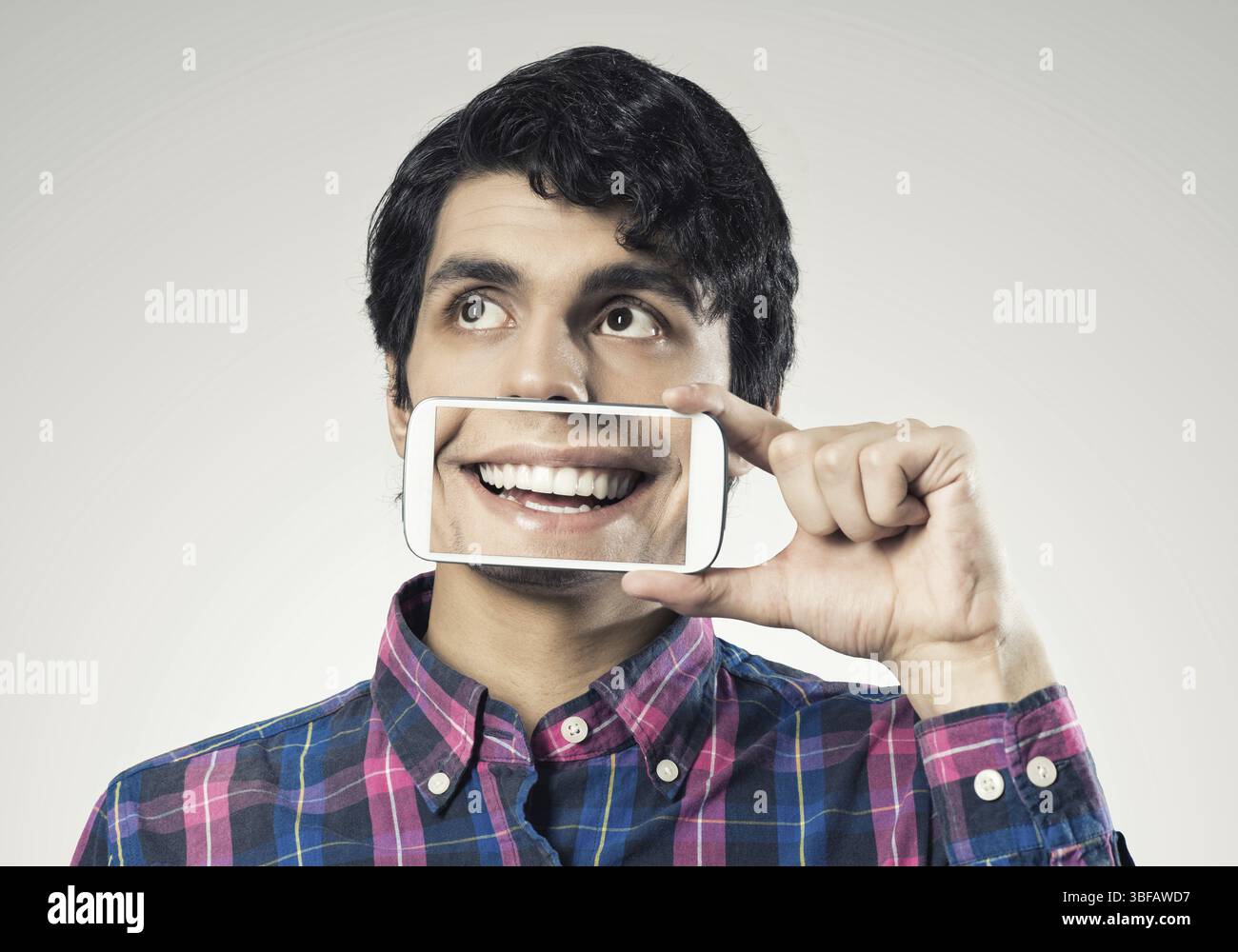 Jeune homme tenant un smartphone avec le sourire à l'écran Banque D'Images