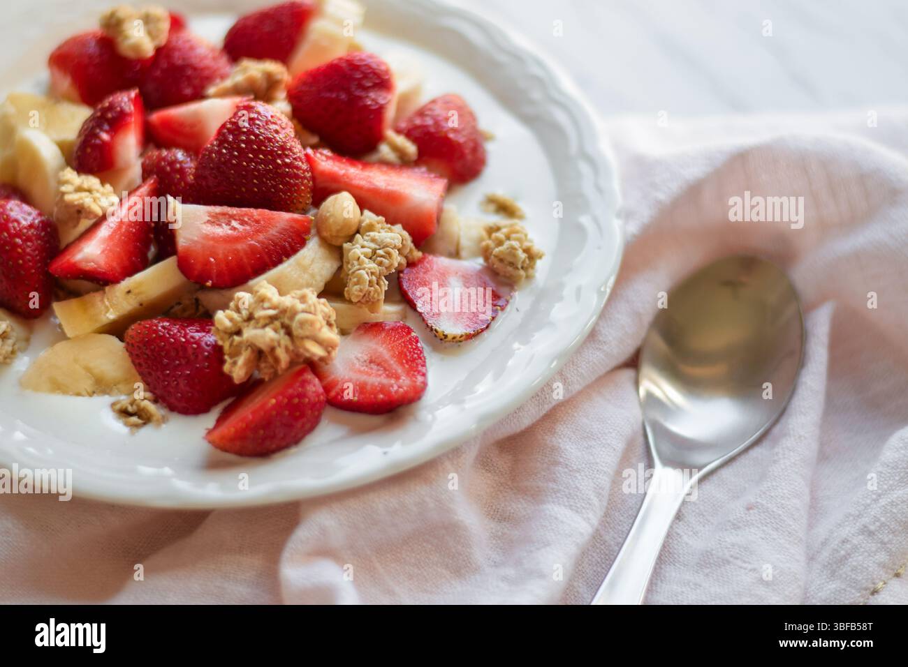 Bol de petit déjeuner avec granola, fraises, bananes et lait Banque D'Images