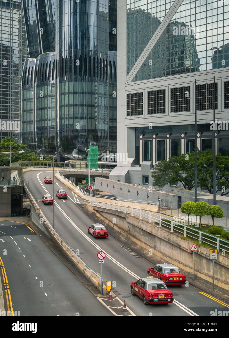 Ligne de véhicules de taxi de style traditionnel de Hong Kong dans le centre-ville de Hong Kong avec des bâtiments qui l'entourent Banque D'Images