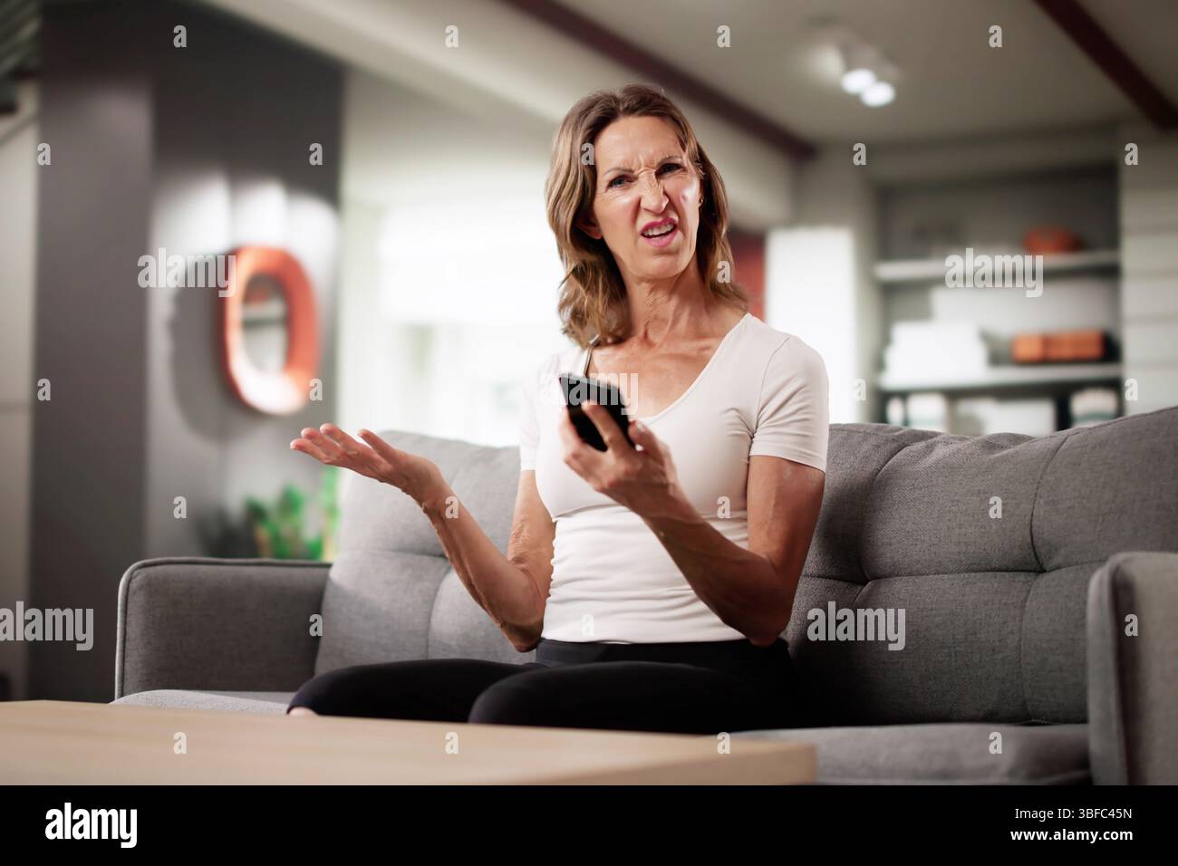 Alerte d'escroquerie financière : femme avec douleur au cou en utilisant un téléphone portable Banque D'Images