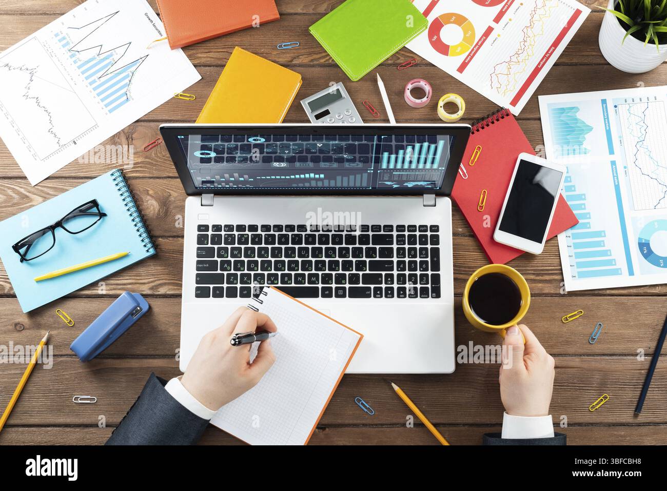 Gros plan des mains d'homme d'affaires travaillant à l'ordinateur portable. Bureau vue de dessus avec ordinateur et documents financiers sur table en bois. Profession commerciale des Banque D'Images