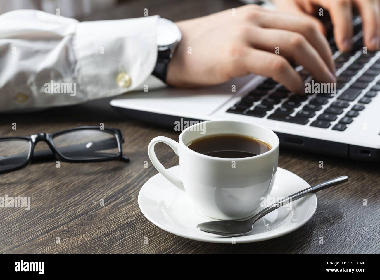 Homme d'affaires assis au bureau et travaillant avec un ordinateur portable. Gros plan des mains de l'homme tapant sur le clavier dans le bureau. Lieu de travail d'homme d'affaires avec des lunettes a Banque D'Images