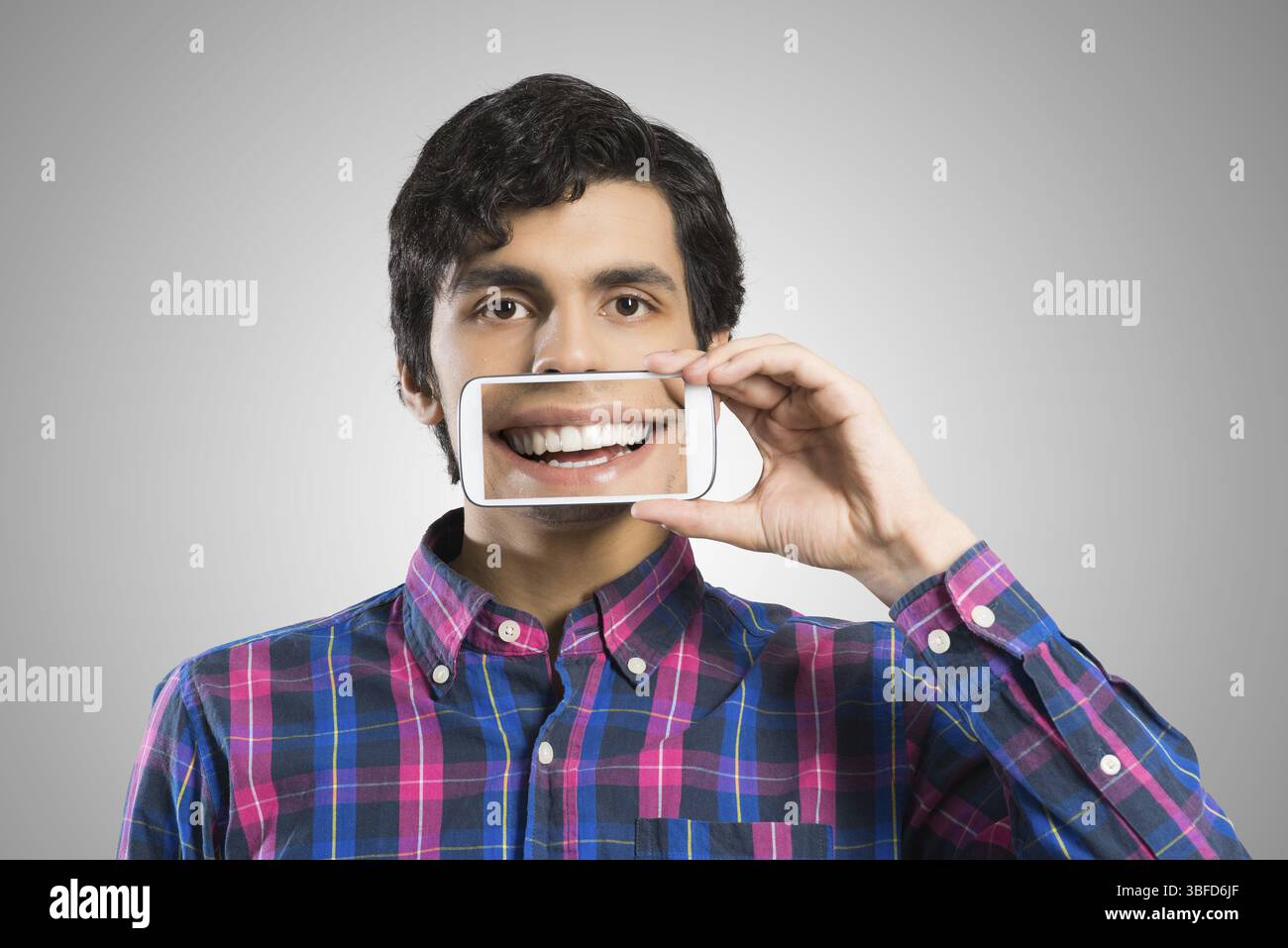 Jeune homme tenant un smartphone avec le sourire à l'écran Banque D'Images