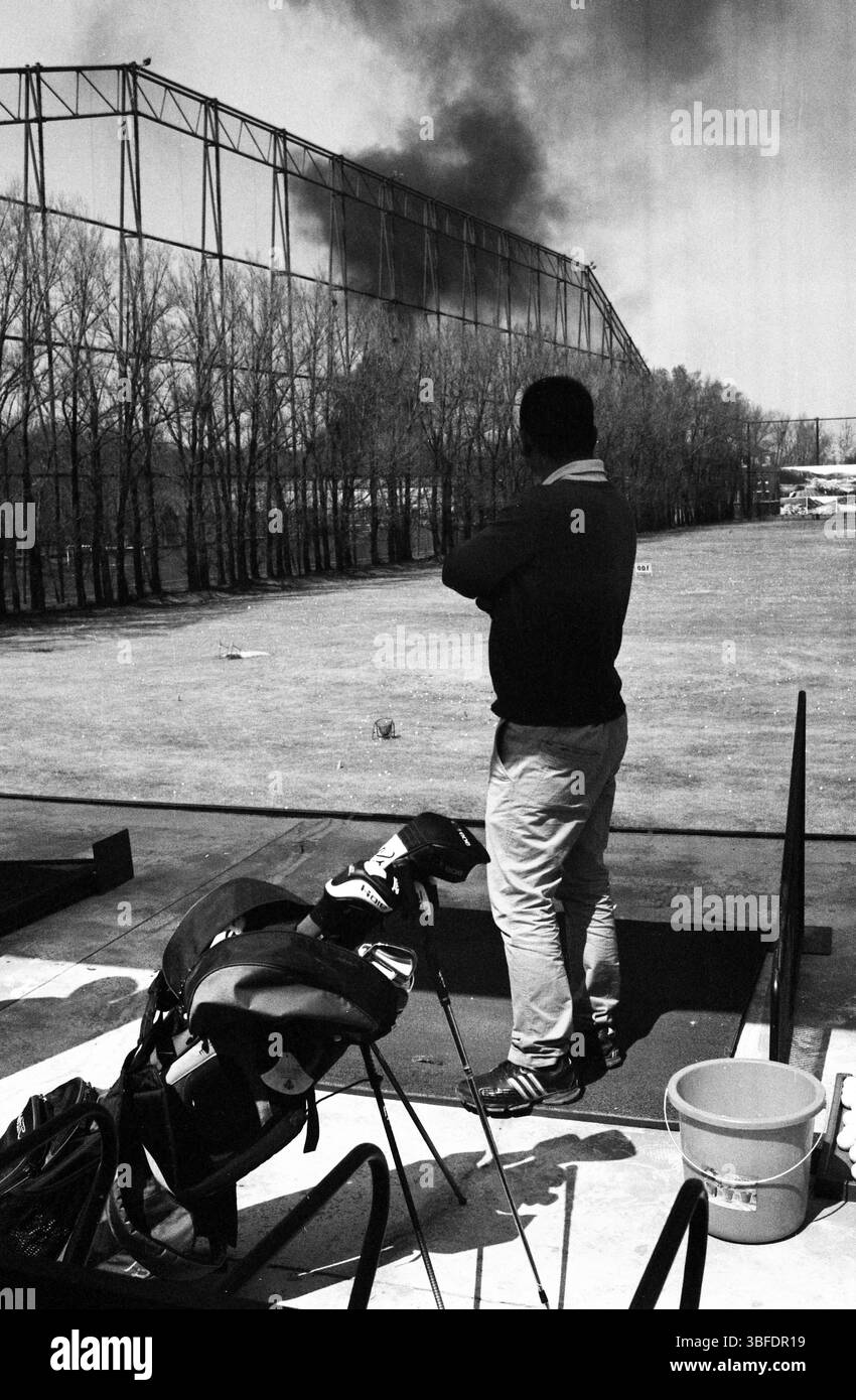 Golfeur sur l'aire d'échauffement regardant la fumée du feu, début des années 2010 en Chine Banque D'Images