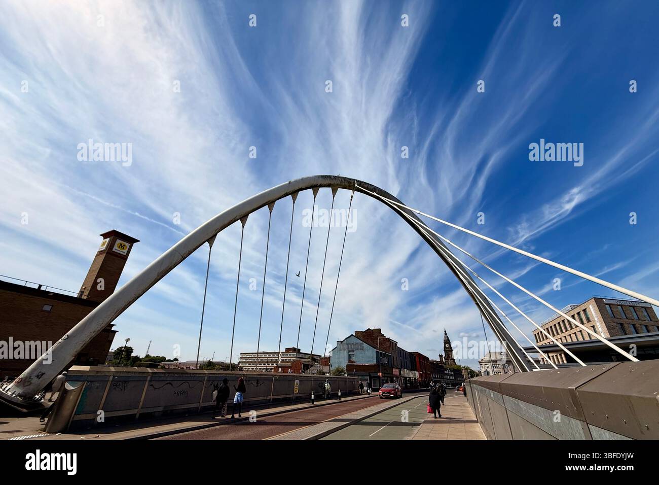 Pont suspendu sur la ligne de chemin de fer sur Newport Street à Bolton contre un ciel bleu avec tour de l'horloge de la mairie à distance Banque D'Images