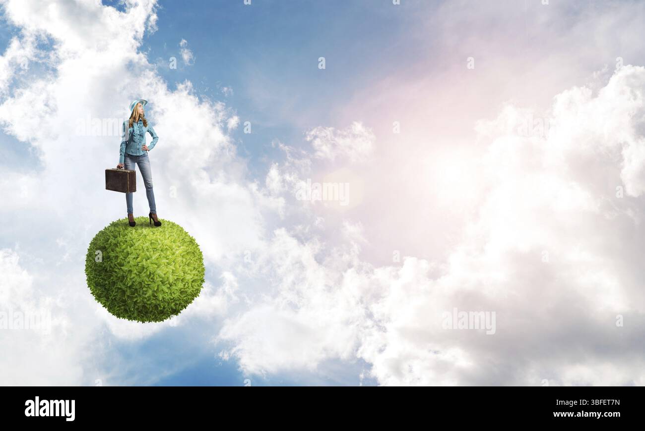 Belle femme voyageuse en chapeau avec valise sur la planète verte Banque D'Images