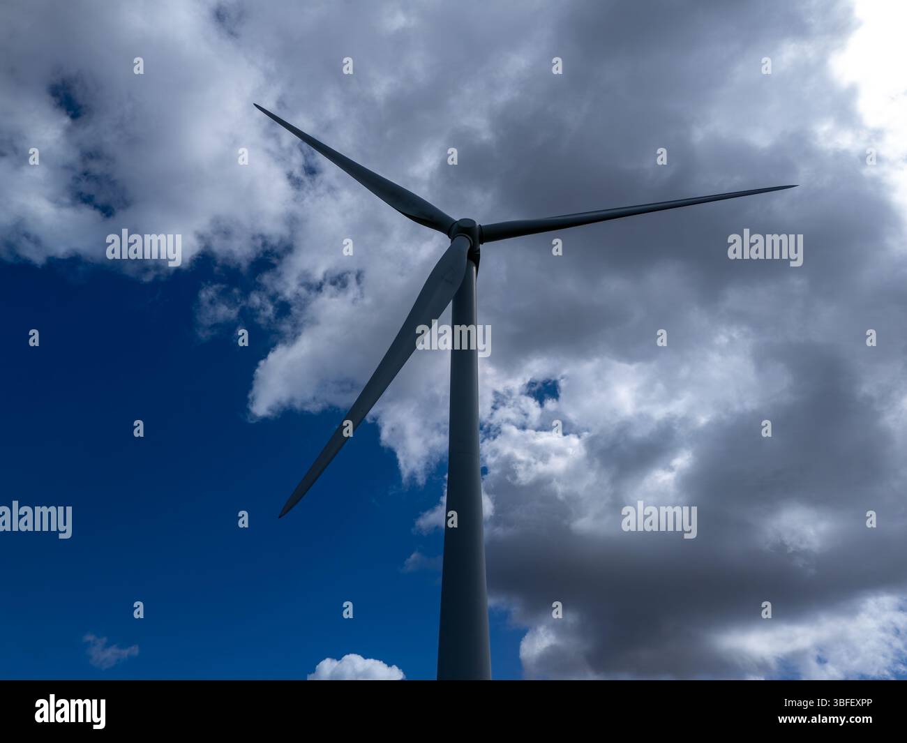 Éolienne tournant contre le ciel bleu avec des nuages blancs spectaculaires, générant une énergie propre et durable Banque D'Images