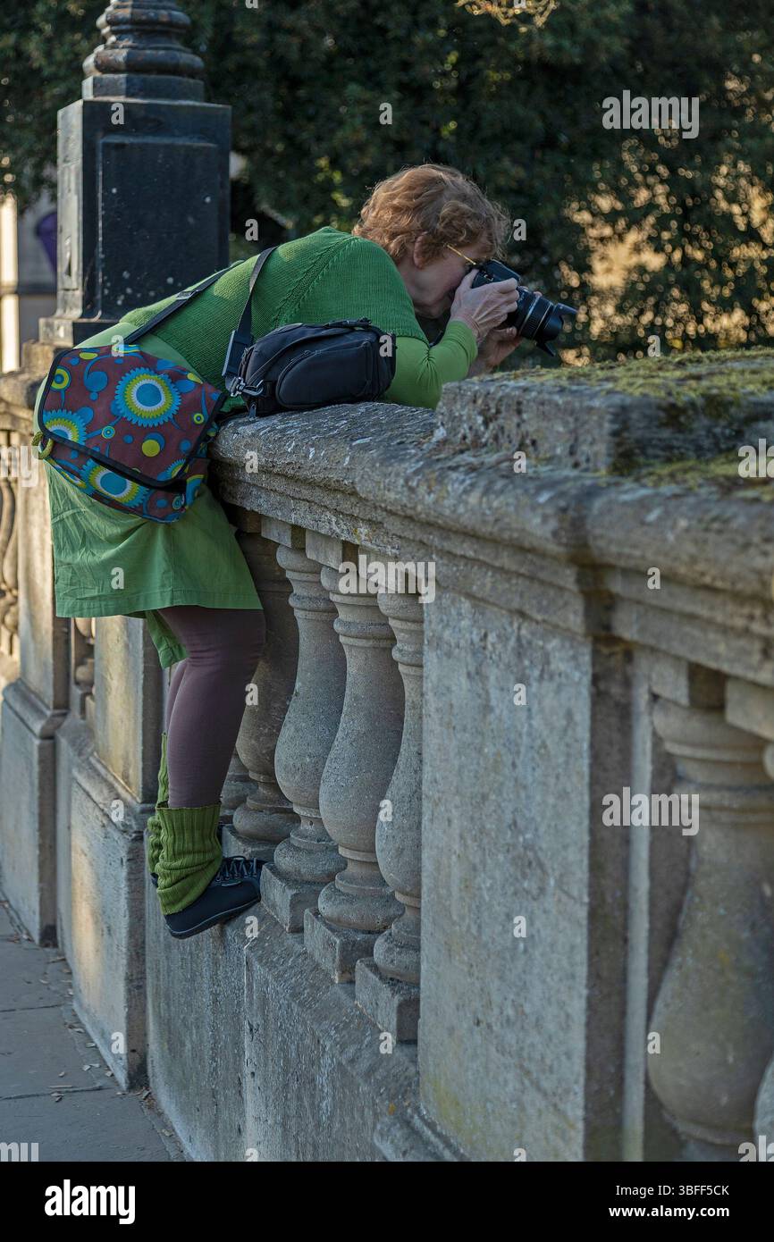Femme âgée a grimpé jusqu'à la clôture et prend des photos à travers la rampe, Magdalen Bridge, Oxford, Angleterre, Grande-Bretagne Banque D'Images