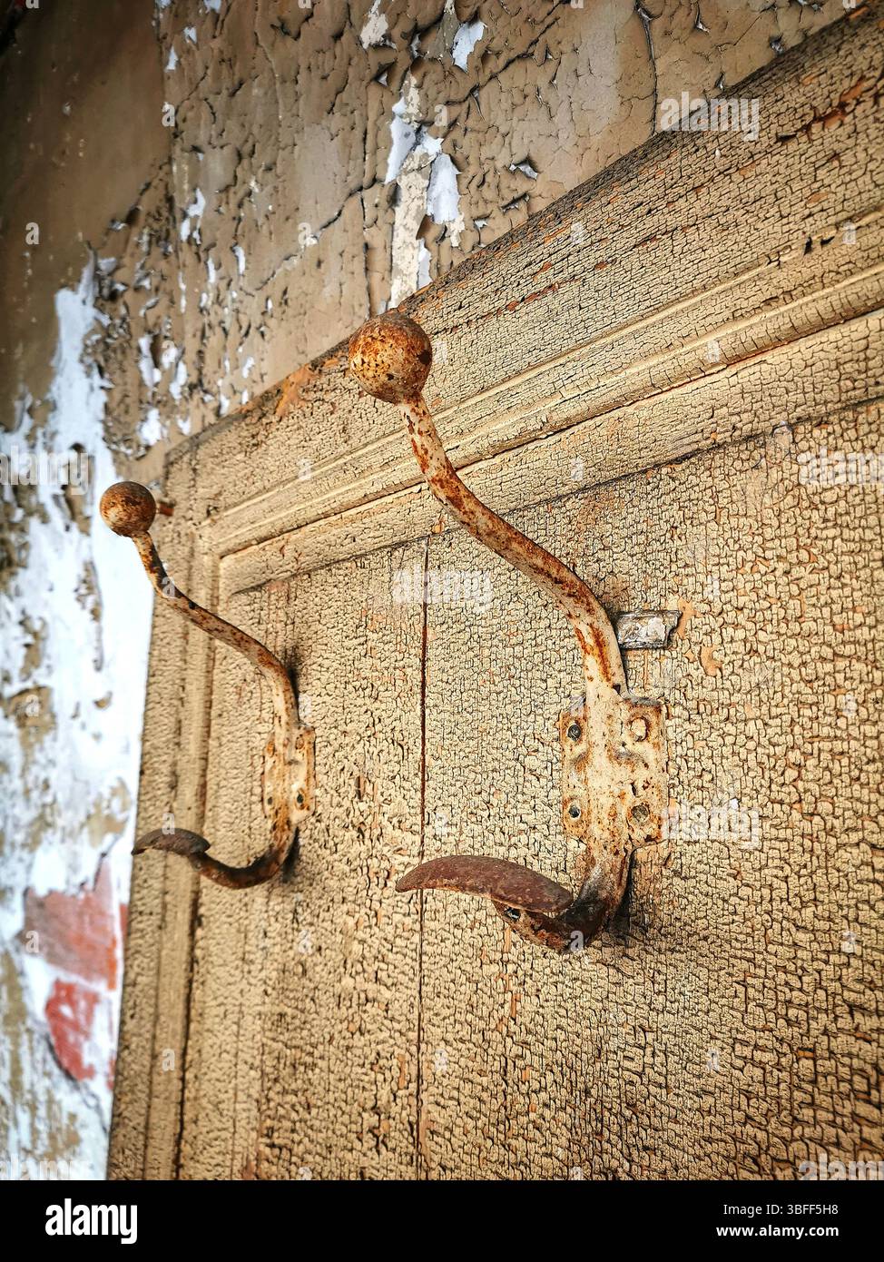Crochets rouillés attachés à un mur altéré dans un bâtiment délabré mettant en évidence la décomposition et l'abandon Banque D'Images