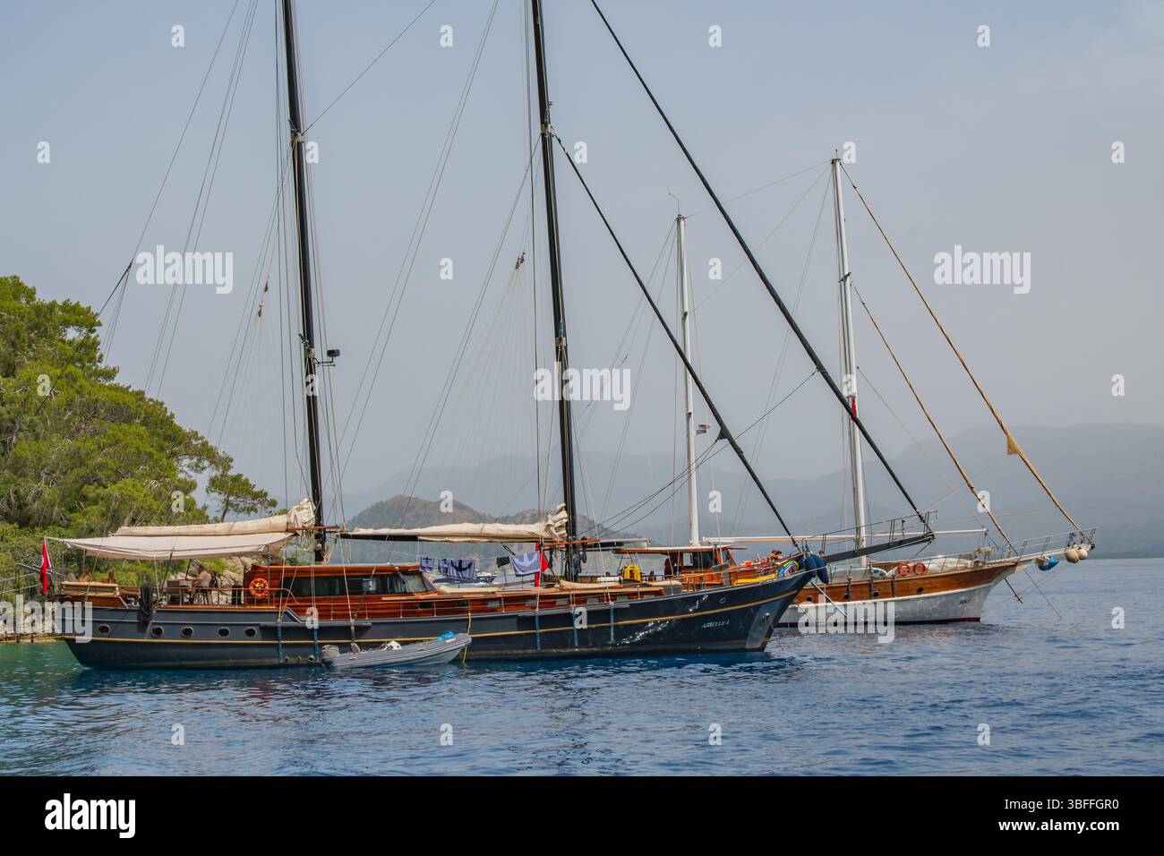 La beauté d'une crique méditerranéenne, où les yachts à voile en bois classiques trouvent un lieu de repos paisible dans une nature intacte.reflétant le charme Banque D'Images