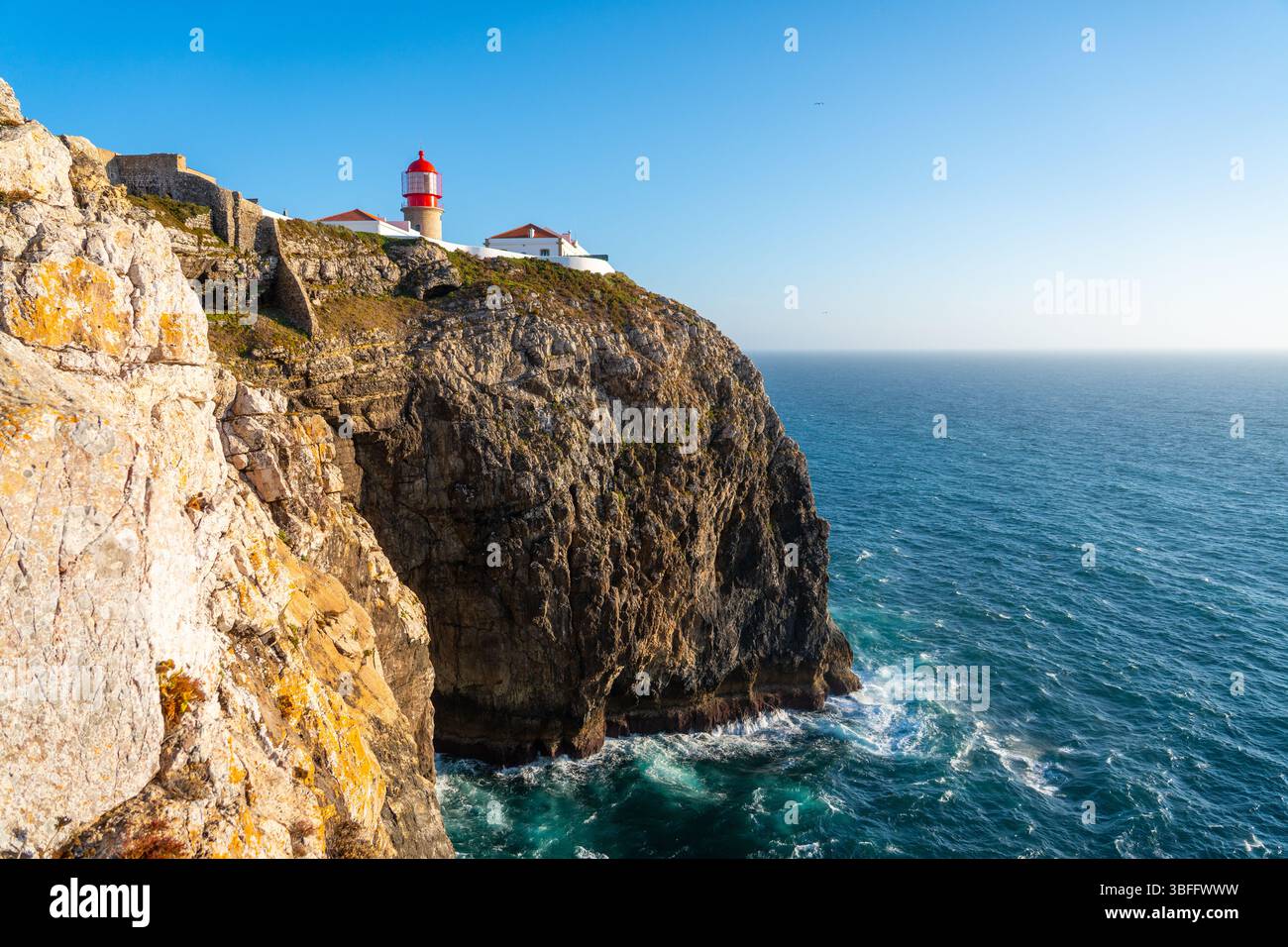 Le phare de Cabo da Roca avec son sommet rouge distinctif est perché sur une haute falaise accidentée surplombant le vaste océan Atlantique et la côte courbe Banque D'Images