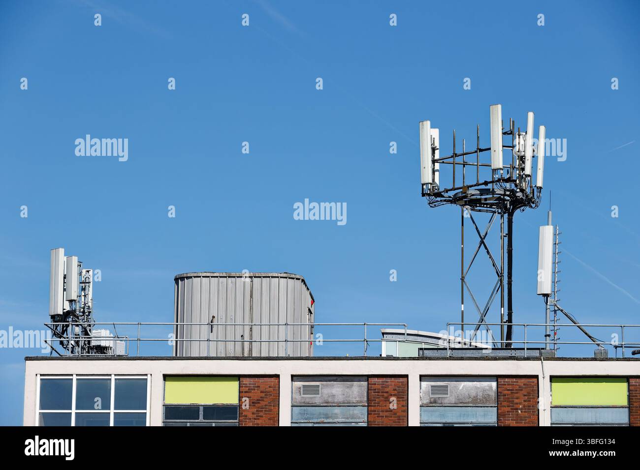 Mât de téléphone portable monté sur le toit du bâtiment avec le ciel bleu et le soleil à Bury Greater manchester uk Banque D'Images