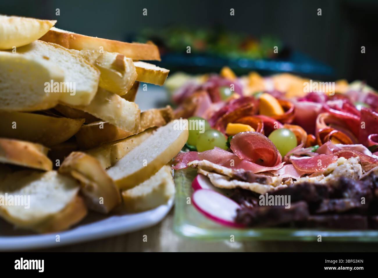 ​​bread tranchés et charcuterie avec assortiment de viandes, fromages, raisins et radis Banque D'Images