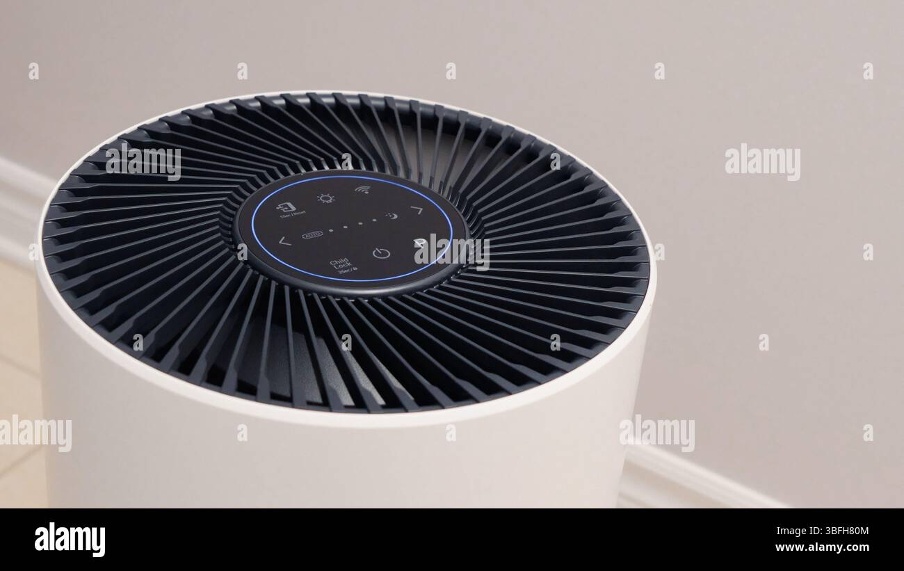 Vue rapprochée du purificateur d'air avec ventilateur noir. Appareil électronique rond noir avec boutons et lumières brillantes sur fond blanc. Banque D'Images