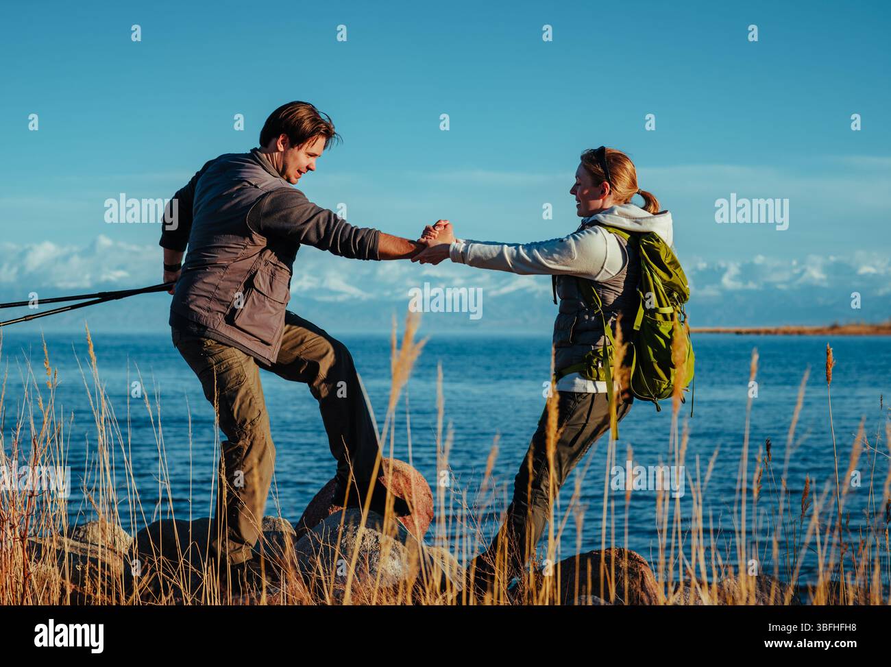 Touristes homme et femme tenant les mains debout sur des pierres sur fond de lac Banque D'Images
