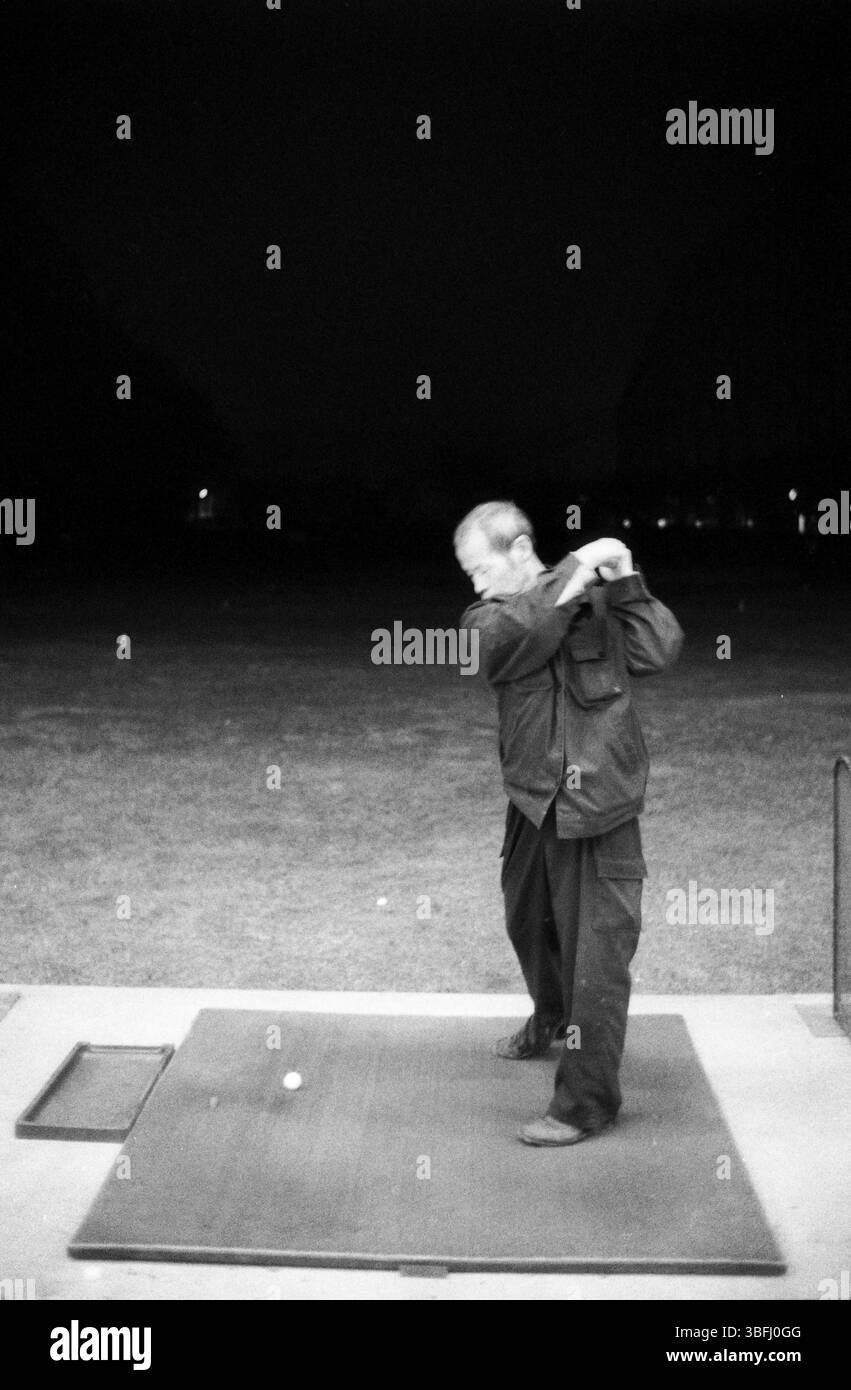 Début des années 2010 Beijing Golf course travailleur avec swing amateur la nuit, Pékin, Chine Banque D'Images