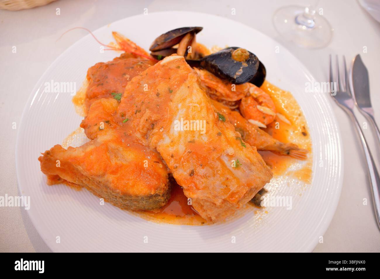 Gros plan de poisson turbot plat avec bar et singes. Un plat espagnol de différentes sortes de fruits de mer cuits dans une sauce riche. Banque D'Images