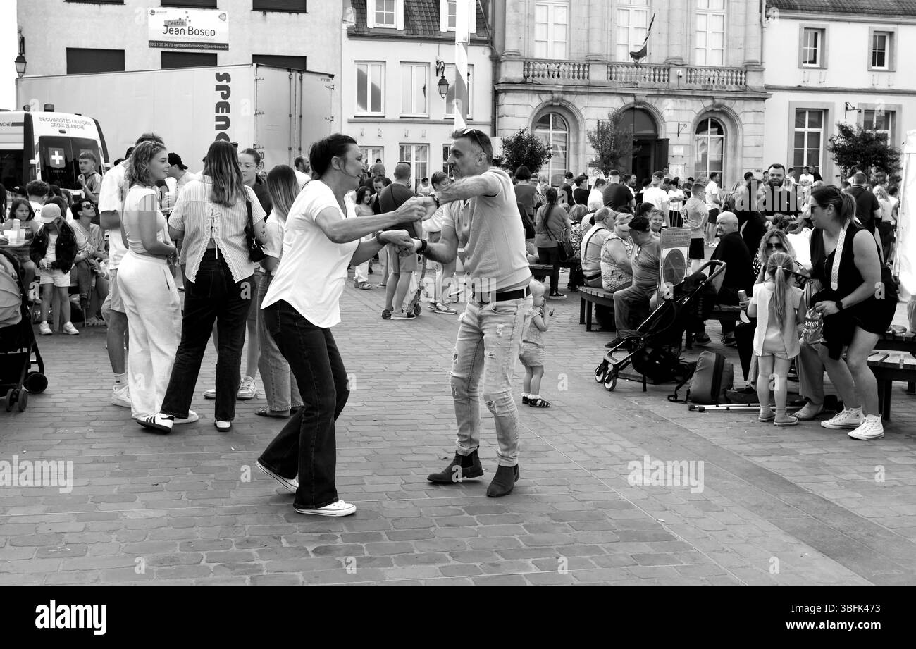 Couples dansant dans la rue pendant le jour de mai célébrations de la Fête du Muguet (jour de la Lilly de la Vallée) le jour de la fête du travail à Guines dans le nord de la France 2025 Banque D'Images