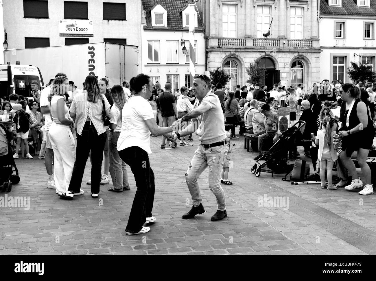 Couples dansant dans la rue pendant le jour de mai célébrations de la Fête du Muguet (jour de la Lilly de la Vallée) le jour de la fête du travail à Guines dans le nord de la France 2025 Banque D'Images
