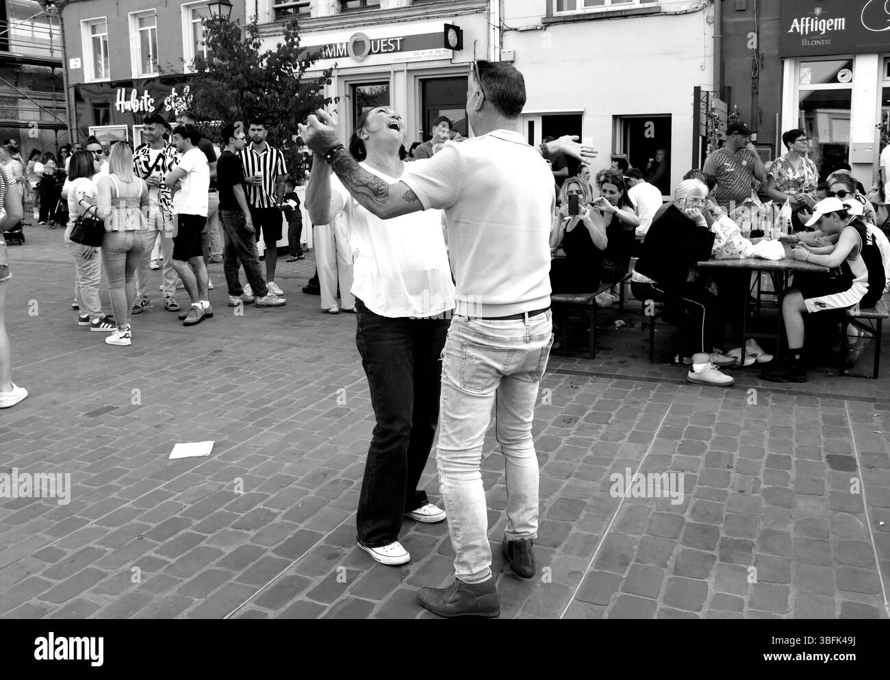 Couples dansant dans la rue pendant le jour de mai célébrations de la Fête du Muguet (jour de la Lilly de la Vallée) le jour de la fête du travail à Guines dans le nord de la France 2025 Banque D'Images