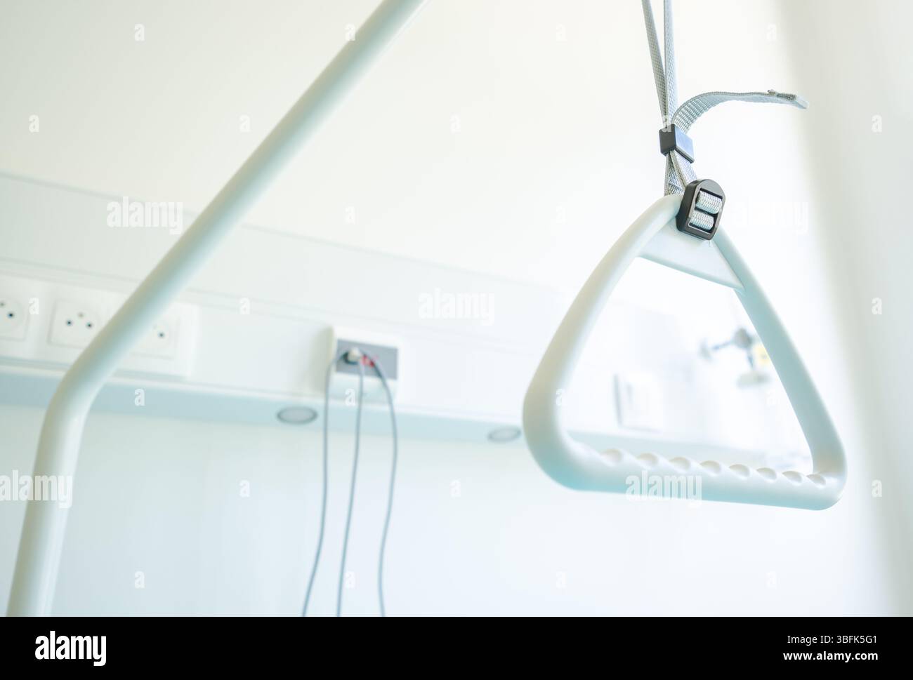 Une barre d'appui est suspendue à une structure de support dans une salle d'établissement médical bien éclairée conçue pour l'assistance et la sécurité des patients pendant la rééducation physique Banque D'Images