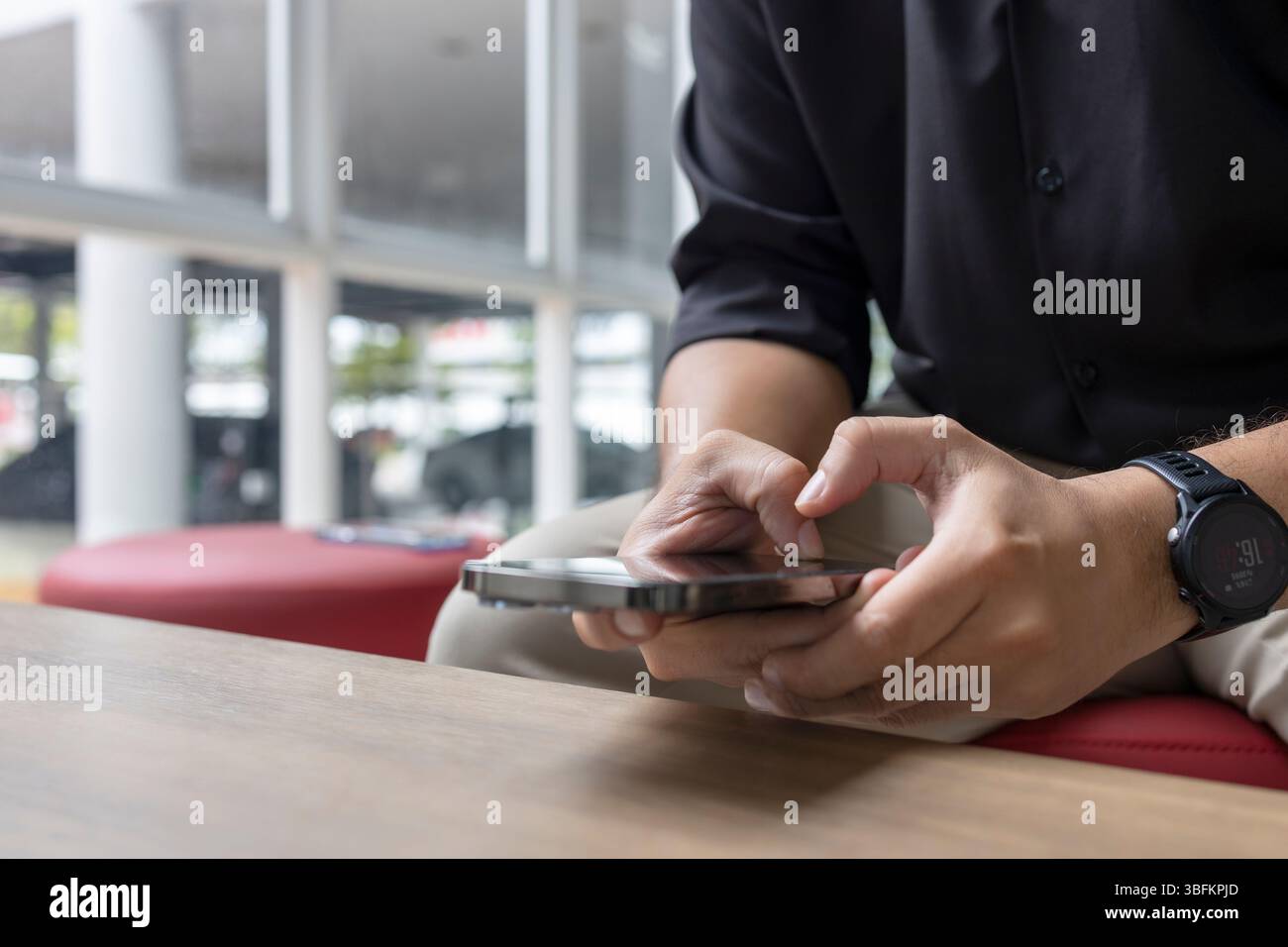 Gros plan d'un homme utilisant un smartphone dans un espace intérieur moderne. Style décontracté d'affaires, détente, style de vie technologique, concept de communication. Banque D'Images