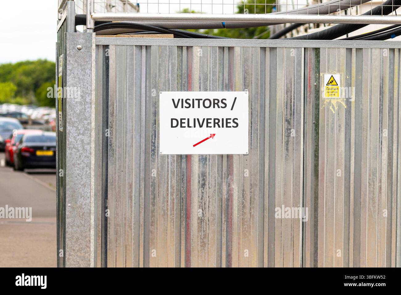 Les visiteurs et les livraisons signent sur une clôture en acier massif. Banque D'Images