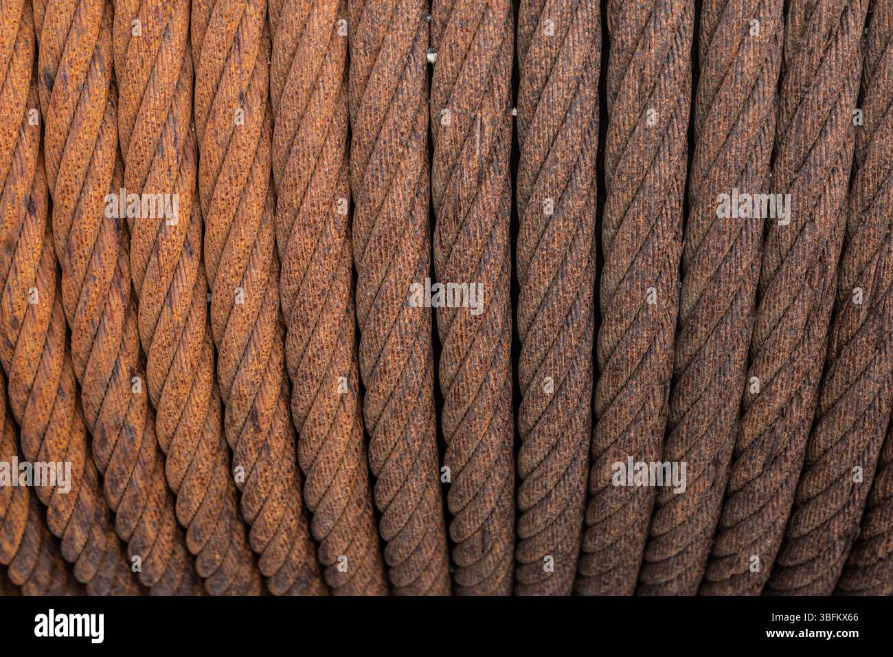 Câbles métalliques rouillés enroulés sur une bobine, photographiés dans un chantier naval norvégien désarmé. Gros plan industriel avec détails de texture forts. Banque D'Images