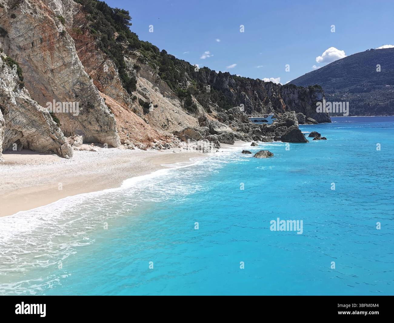 Eaux turquoises et sable blanc immaculé et galets de la plage Afales sur la côte nord de l'île d'Ithica en Grèce. - Image de stock capturée avec un smartphone