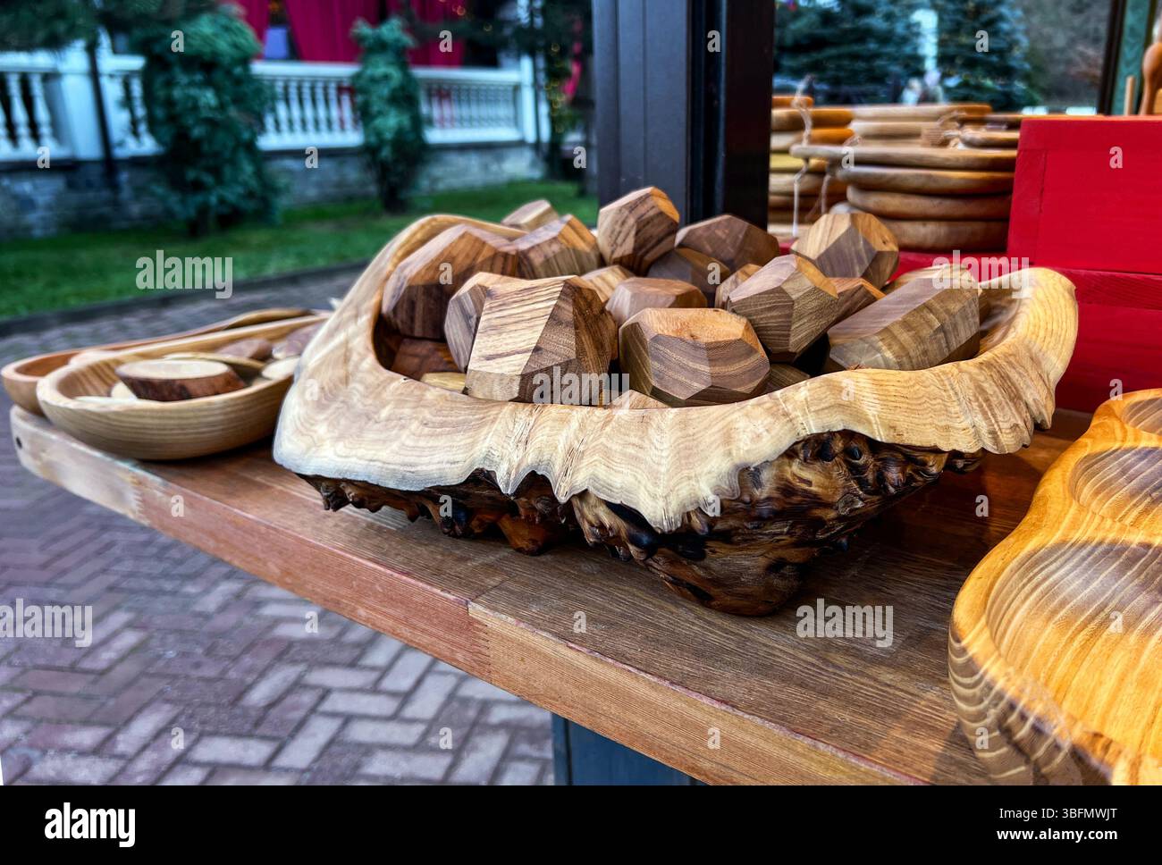 bol en bois magnifiquement sculpté rempli de sculptures géométriques en bois affichées sur une table en bois. Des plats en bois rustiques sont disposés autour, highligh Banque D'Images