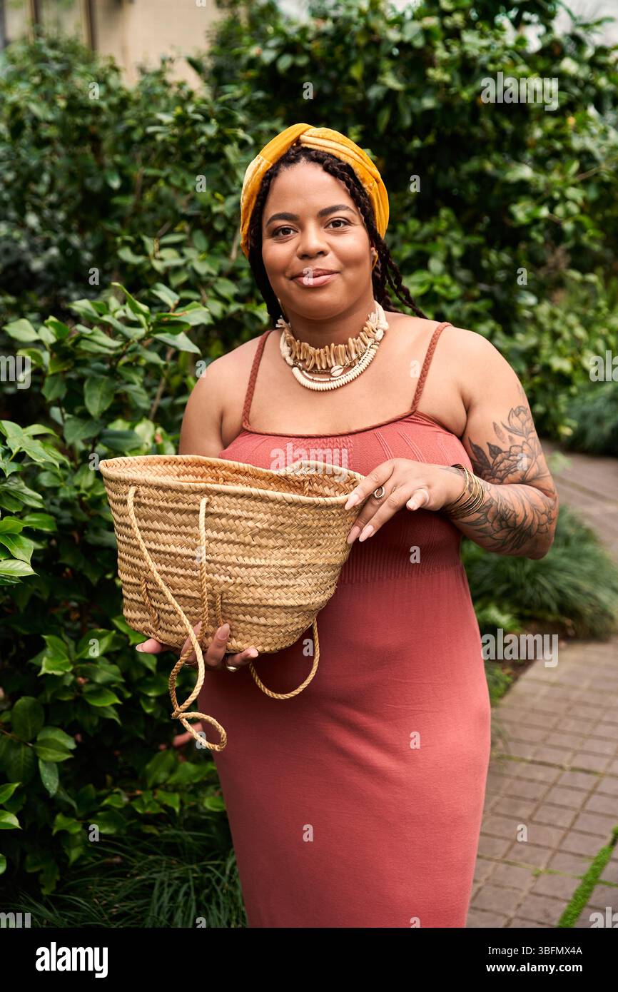 Une joyeuse femme afro-américaine avec des tresses tient un panier, immergé dans des plantes vibrantes. Banque D'Images