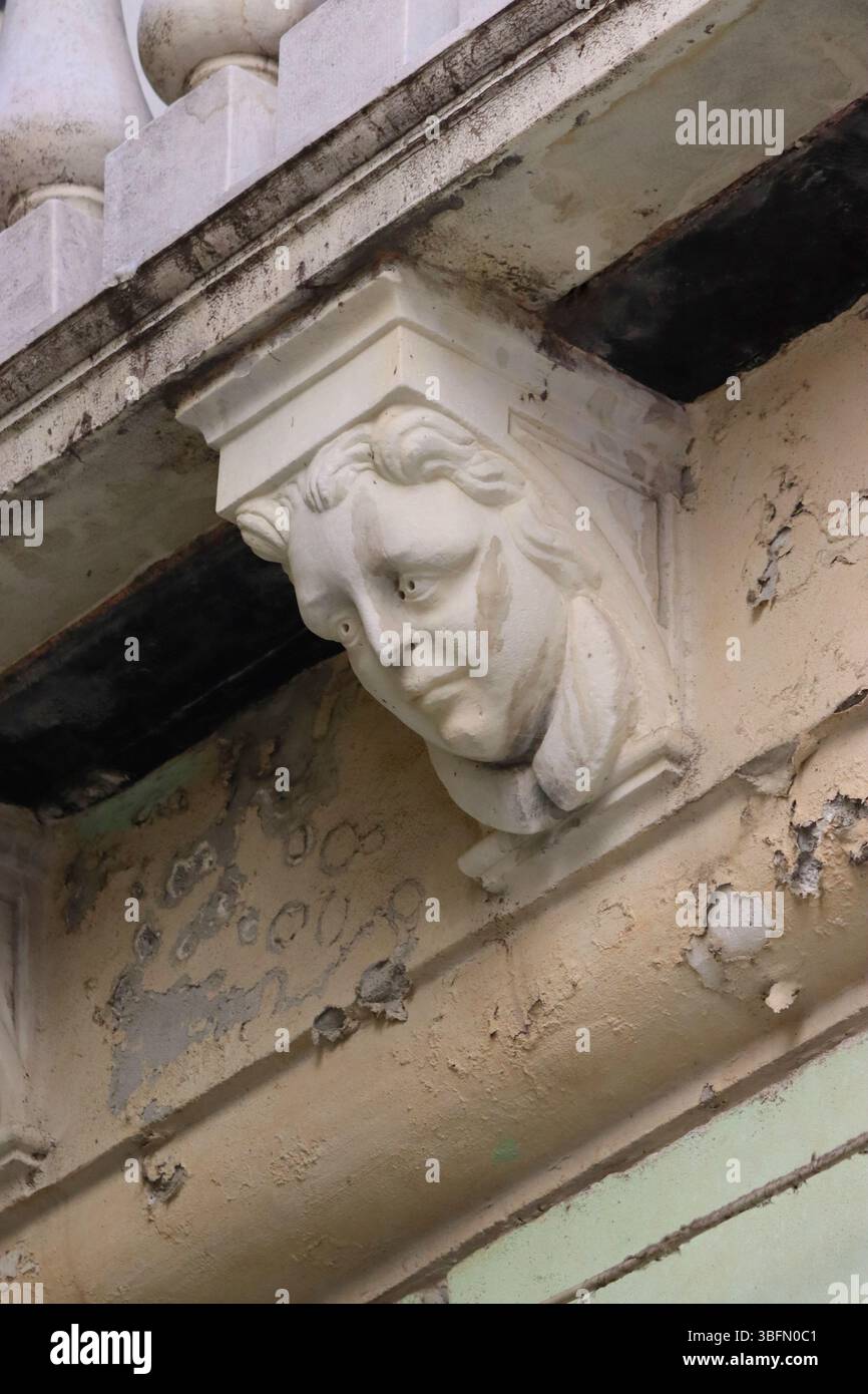 Un corbeau décoratif en pierre sculptée avec un visage regardant vers le bas les piétons dans une rue étroite de Gênes, en Italie. Banque D'Images