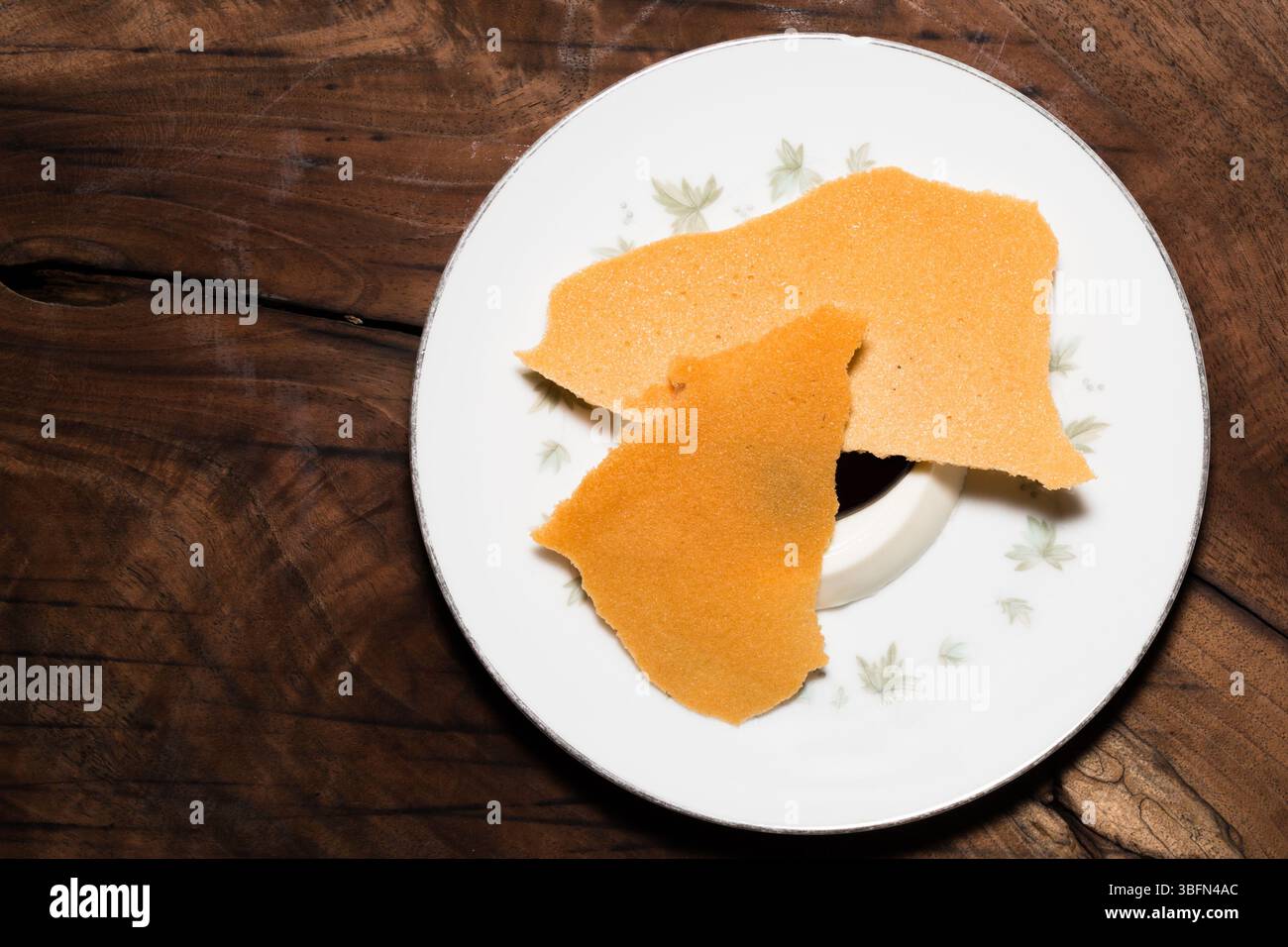 Deux gaufrettes croustillantes sont servies avec un dessert crémeux sur une assiette décorative, offrant une friandise sucrée sur une table en bois. Banque D'Images