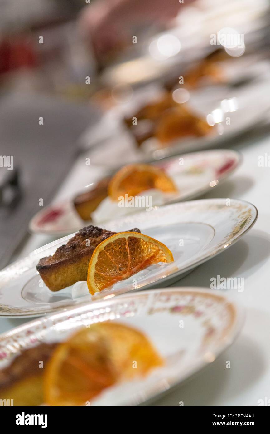 Un chef prépare des desserts avec des oranges confites, ajoutant une touche d’élégance à la présentation. Banque D'Images