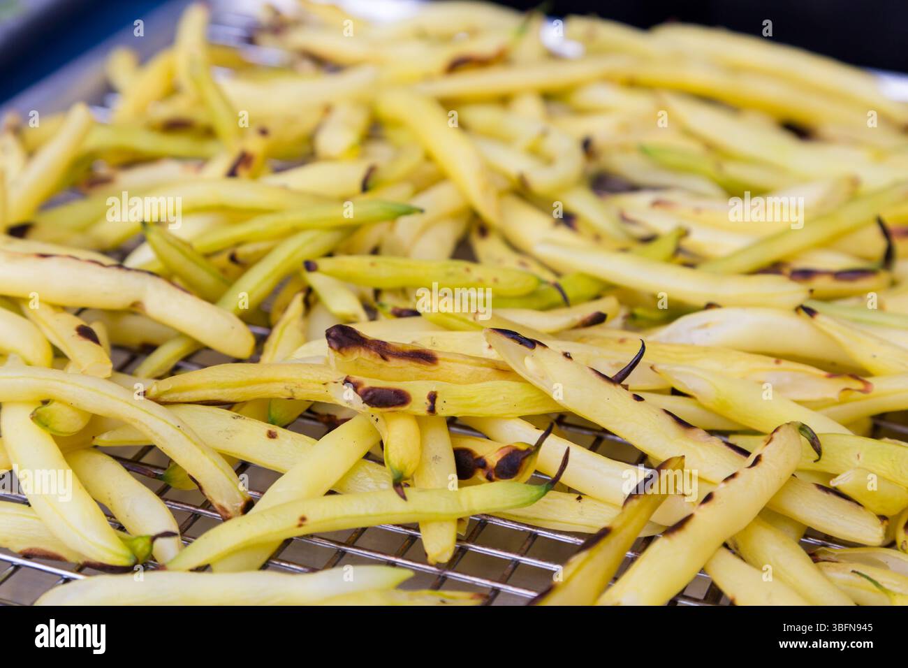 Les haricots jaunes de cire sont grillés sur une grille en métal, créant une saveur fumée et une texture tendre pour un plat d'accompagnement sain. Banque D'Images