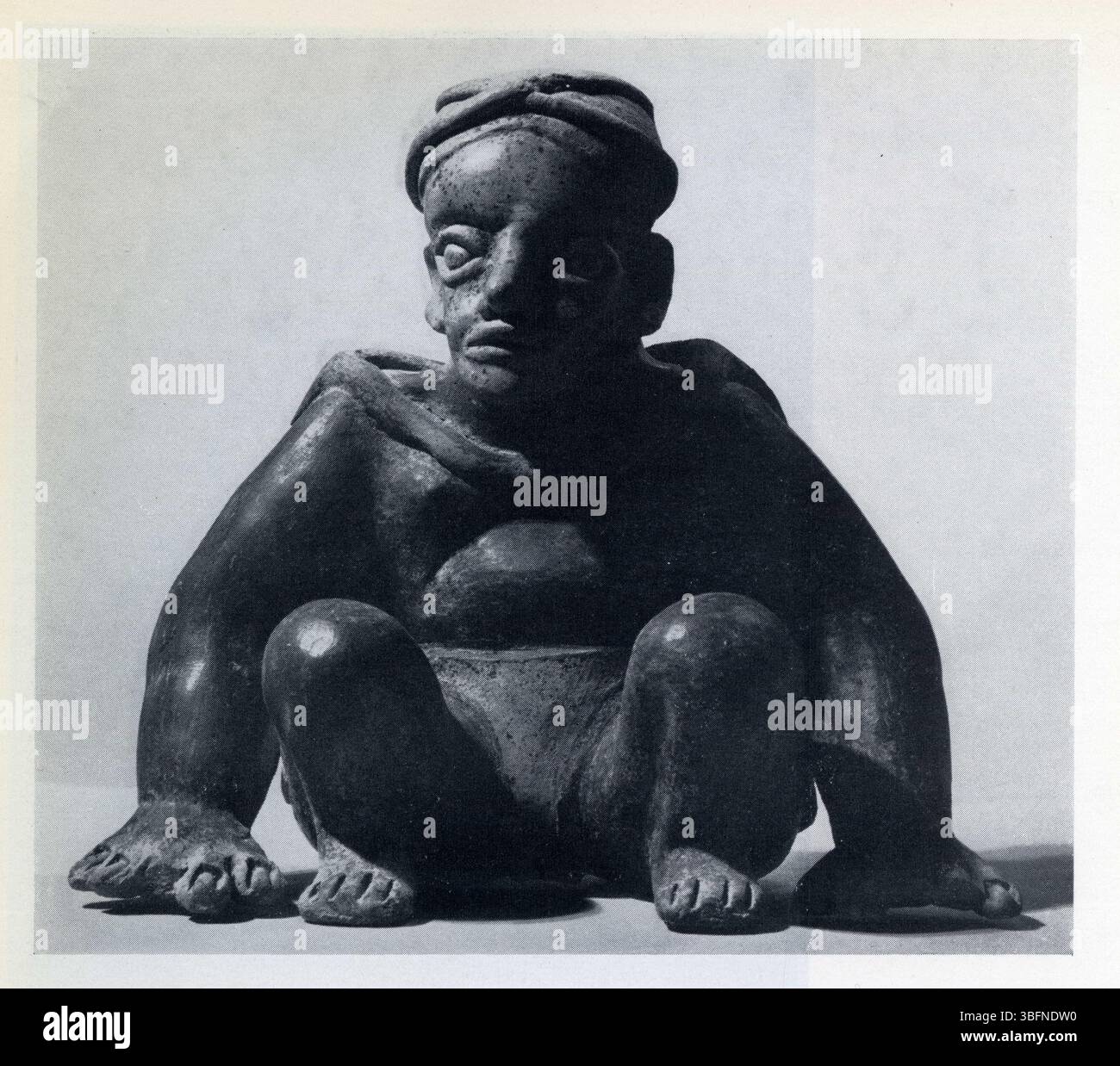 Athlète assis,les mains au sol.le dos est couvert d'une cape.Terre cuite crème polie et rouge sombre polie.époque classique.400-700 après J.C. Banque D'Images