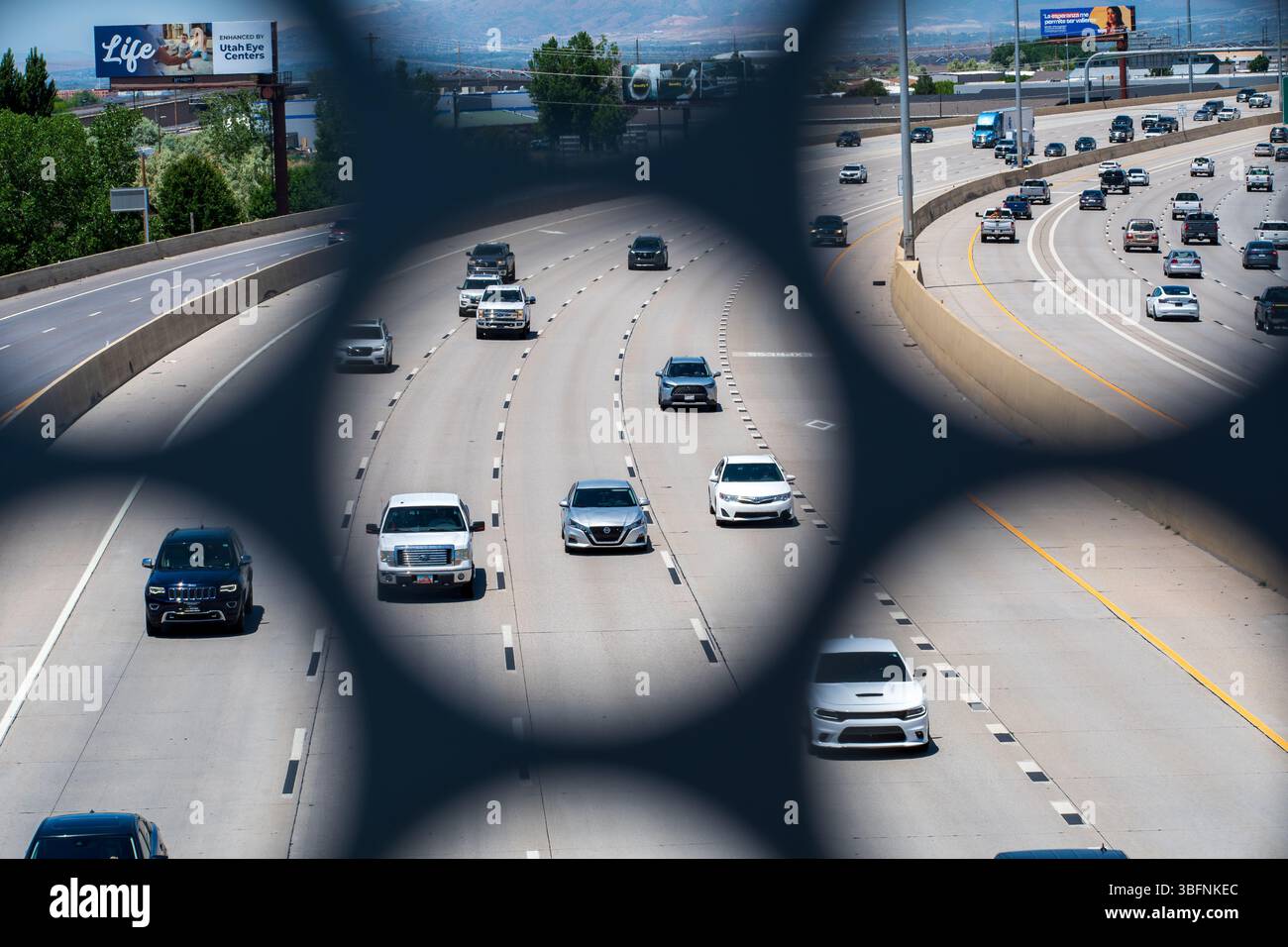 Orem, Utah – 2 juin 2025 : la circulation en direction du nord se déplace le long de l'Interstate 15 comme vu à travers une ouverture structurelle dans le pont piétonnier UVU à Orem, UT. Banque D'Images